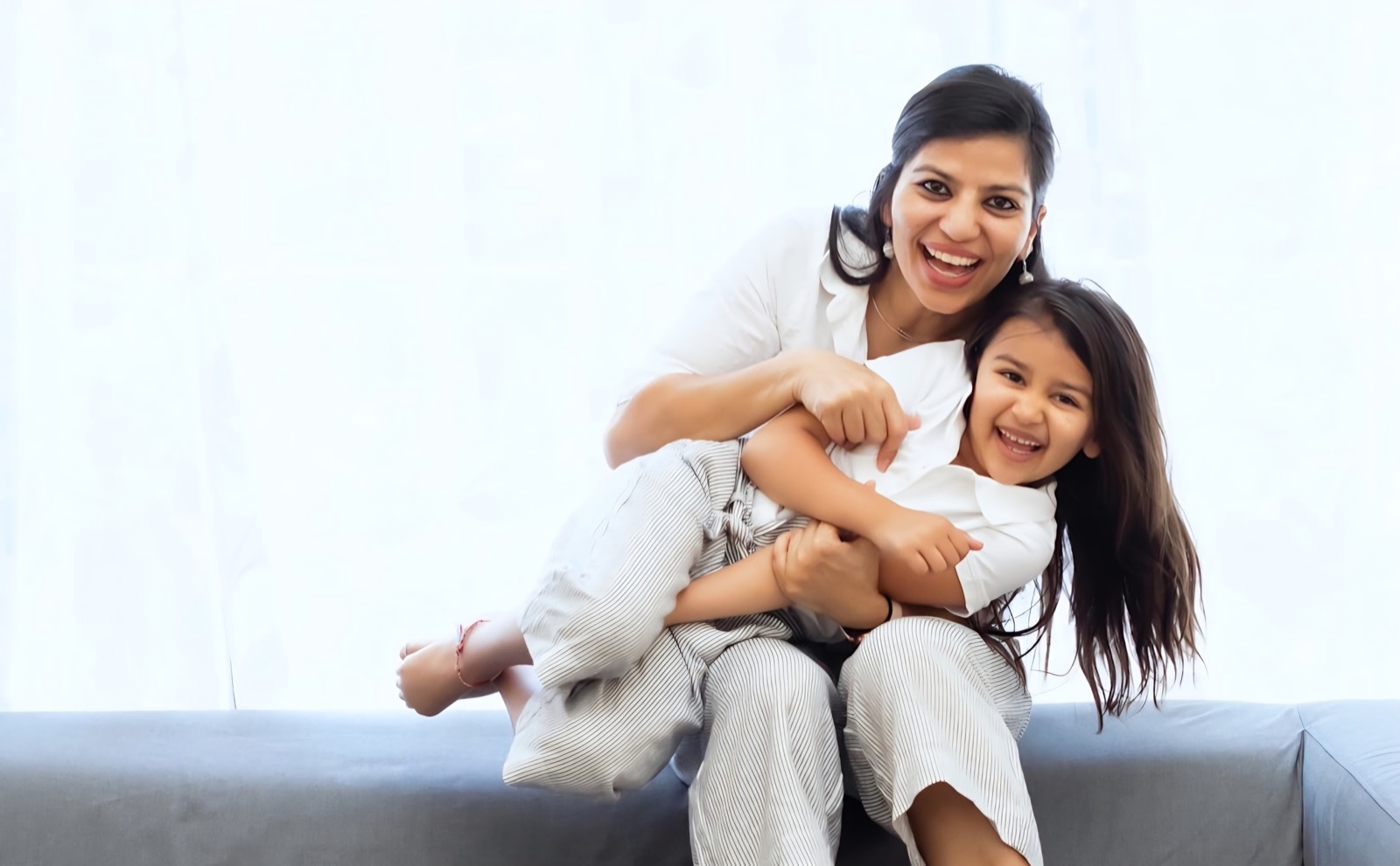 A smiling mother holding her laughing young daughter