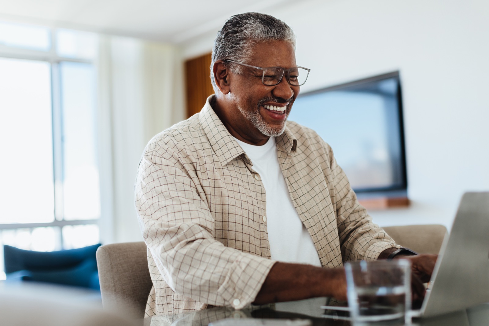 A smiling man booking a dental appointment online on his laptop at home